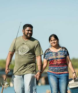 Couple walking along peer with fishing rod