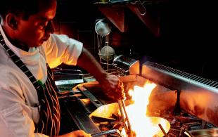 Chef cooking at stove, pan is on fire