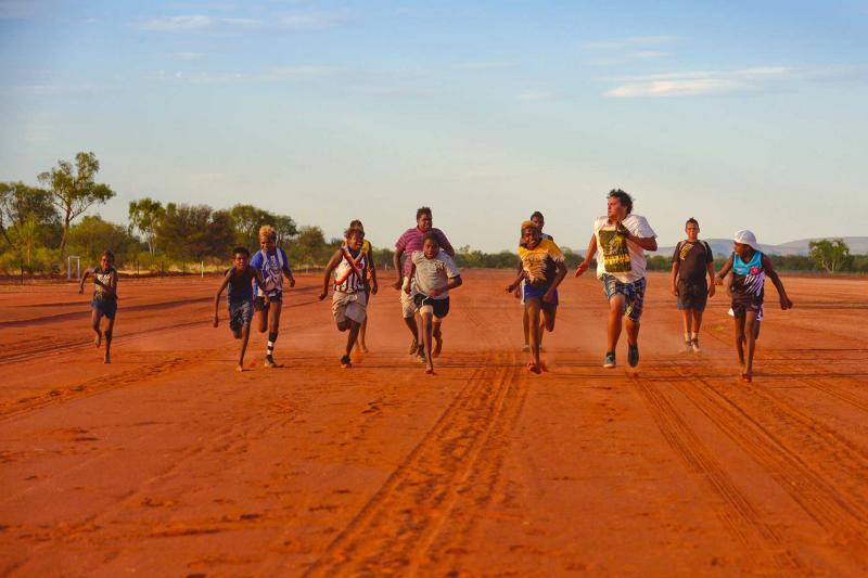 Children running a race on a red dust road