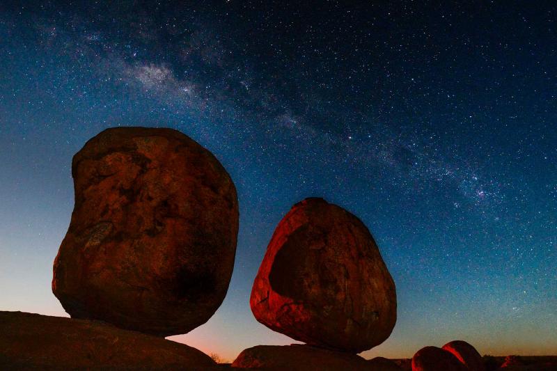 Devils Marbles at night with the sun setting and stars in the background