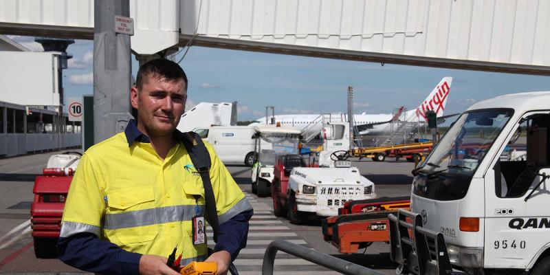 Workman standing beside vehicles at airport